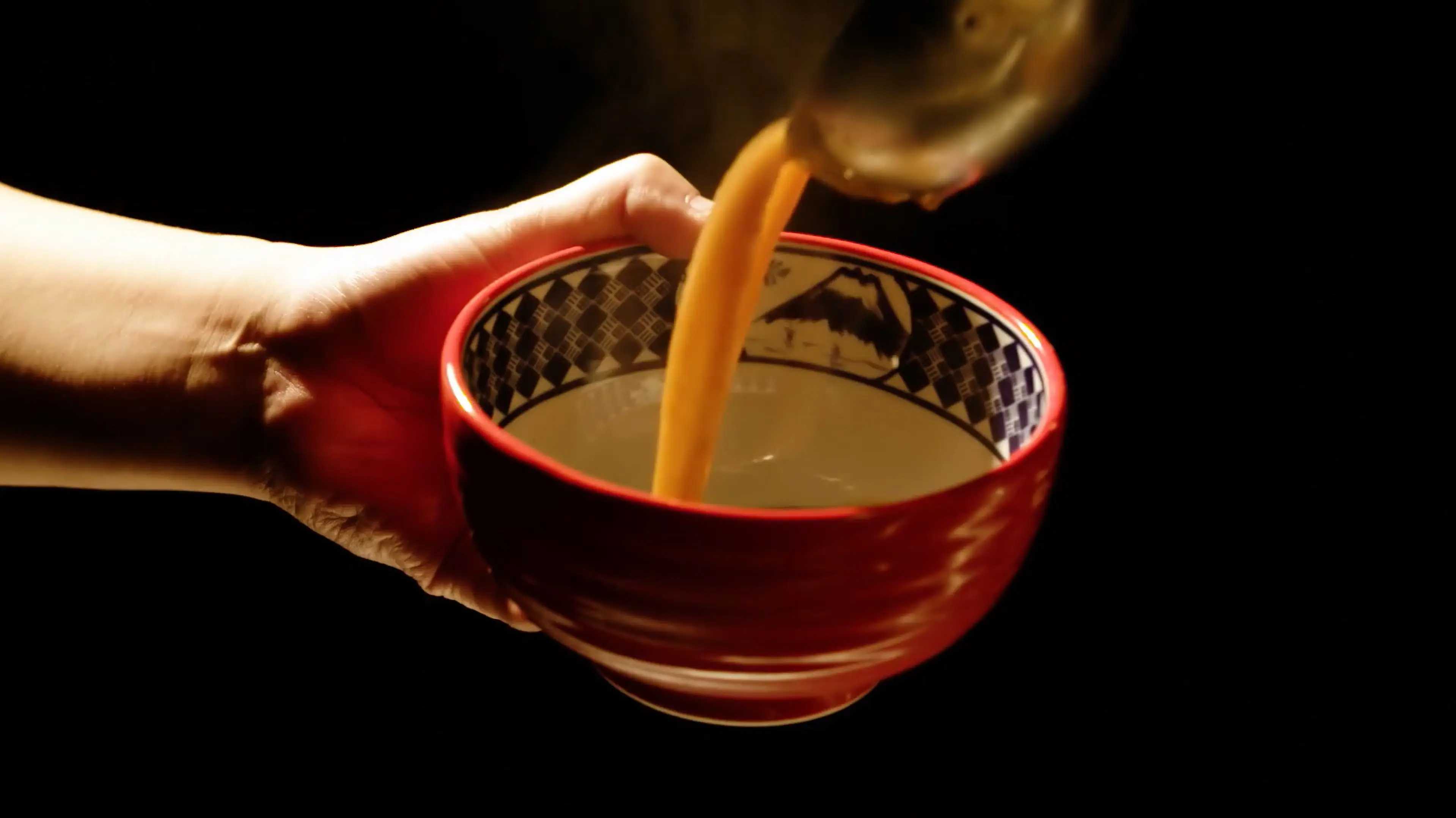 器に濃厚豚骨魚介スープを注ぐ様子